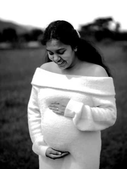 A tender black and white portrait of the mom-to-be looking down at her bump with a smile. The soft focus and simple composition make it a very emotional image.