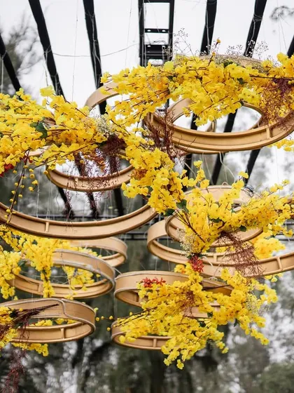 For this bar decor, we went with an unconventional autumn theme. We created a hanging installation of interlocking rings adorned with bright yellow florals, creating a sculptural and eye-catching piece above the bar.