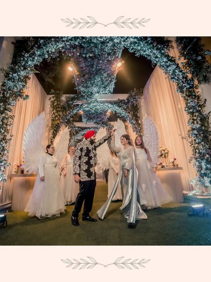 A grand, fairytale entrance for Gurbani and Gurneet, flanked by performers with angelic wings. This shot captures the theatrical and magical atmosphere of their celebration.