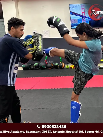 A young student executes a perfect high kick during a pad work session. We focus on building not just power, but also flexibility, balance, and precision in every technique we teach.