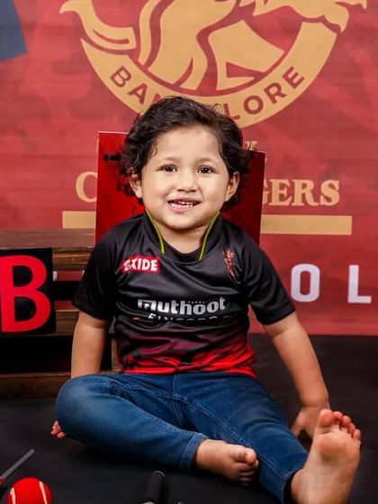 A smiling toddler enjoying the RCB cricket-themed photoshoot. His genuine happiness shows how much fun these sessions can be.
