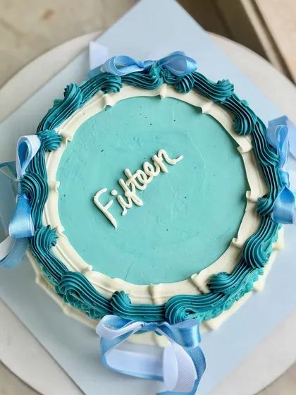 An overhead shot of the vintage-inspired "Fifteen" cake, highlighting the clean script and the beautiful contrast between the teal, dark teal, and white buttercream piping.