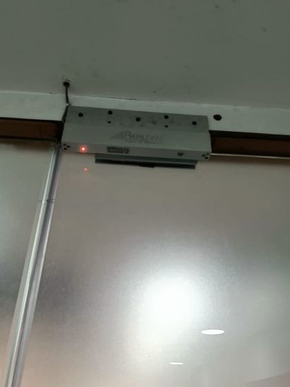 The EM lock connected to the budget-friendly access reader, installed on a frosted glass door. This shows that affordable systems can still be effective.