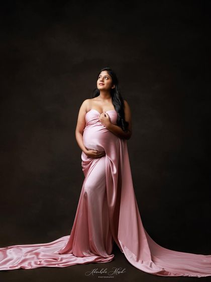 Looking up with a sense of hope, this mother-to-be is a picture of elegance in a flowing pink satin gown.