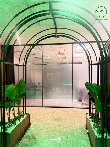 This arched walkway, lined with planters, creates a unique transitional experience within the office. It is designed to feel like a gateway, separating work zones from break areas and adding an element of architectural interest.