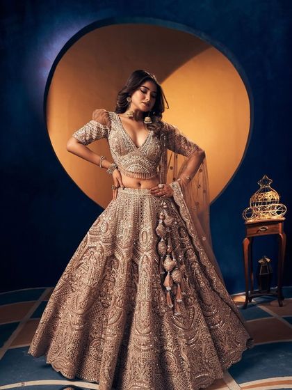 A full shot of the model in the bronze-gold lehenga, looking powerful and glamorous.