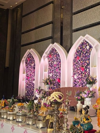 A side view of the purple floral arches, showing the offering table with traditional dolls and silver props.