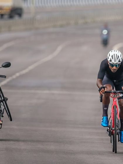 A support moto with a spare wheel rides alongside an elite rider, ready to provide assistance if needed.
