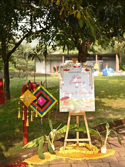 A personalized welcome sign for an outdoor Haldi ceremony. We use easels and custom signage, decorated with local flowers and traditional elements, to greet guests warmly.