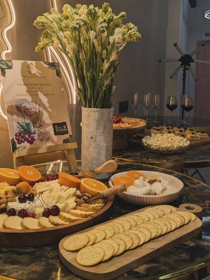An elegant wine and cheese setup for Trims & Tones salon. The marble tables are adorned with cheese boards, crackers, and floral arrangements, creating a chic and sophisticated atmosphere.