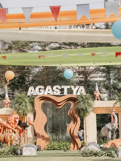 The outdoor venue was transformed into a vibrant jungle with colorful overhead draping, festive buntings, and an expansive play area, ensuring an immersive experience for all the young guests.