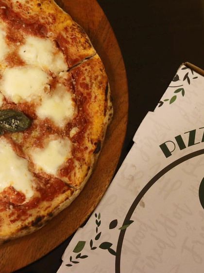 A classic Margherita pizza, sliced and ready to be served, next to one of my custom pizza boxes. Perfect for a cozy night in.