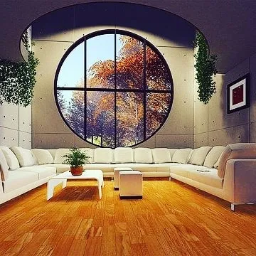 This expansive living area features walls with a smooth, concrete-like finish. The neutral grey texture provides a clean, minimalist backdrop that highlights the room's architectural features, like the large circular window.
