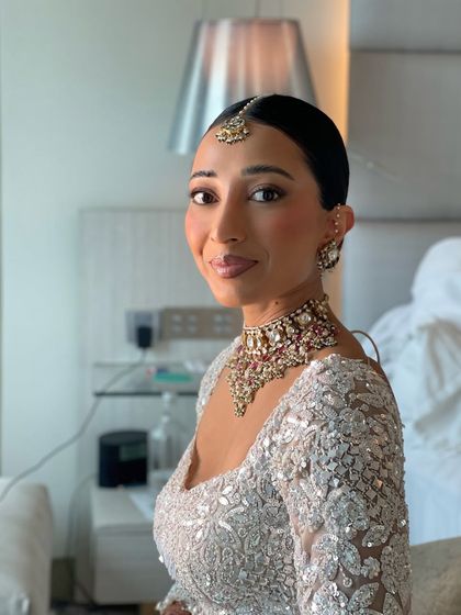 A side profile of the sleek bridal bun. This angle shows how cleanly the hair is pulled back, creating a sophisticated silhouette that allows the bride's makeup and jewelry to shine.