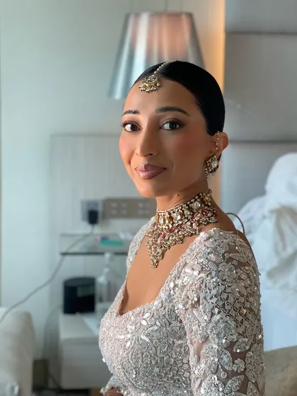 A side profile of the sleek bridal bun. This angle shows how cleanly the hair is pulled back, creating a sophisticated silhouette that allows the bride's makeup and jewelry to shine.