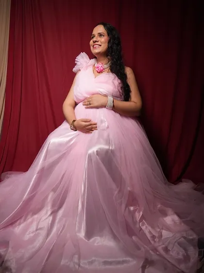 This is the kind of beautiful, happy memory I help create. A client enjoying her maternity photoshoot in a lovely pink gown against our rich red backdrop. The professional lighting makes sure your glow is captured perfectly.