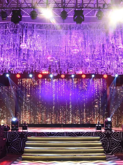 This Sangeet stage is pure glamour, with a ceiling of shimmering silver tassels and disco balls above a sparkling LED backdrop, ready for a night of performances.