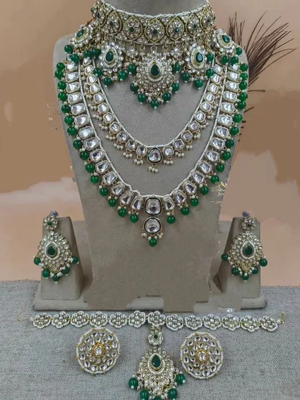 A complete bridal set in emerald green Kundan, including a choker, rani haar, and all matching accessories.