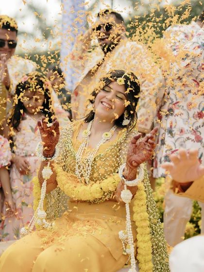 A shower of flower petals for the happy Haldi bride. Her dewy makeup stayed put through all the celebrations, ensuring she looked radiant and joyful.