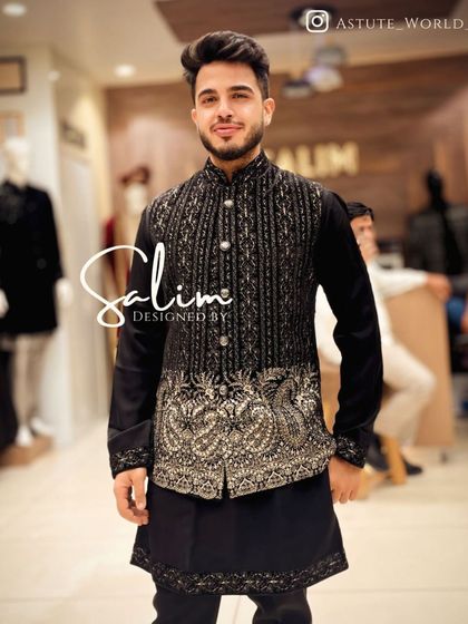 A client in a black kurta paired with a heavily embroidered waistcoat. The waistcoat features intricate silver and gold paisley designs, elevating the entire outfit.