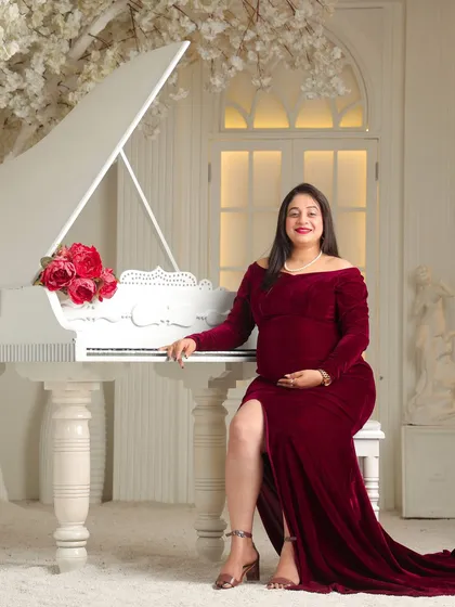 A portrait of pure elegance. In my studio, I use classic props like this white grand piano to create a sophisticated and timeless setting for your solo maternity pictures.