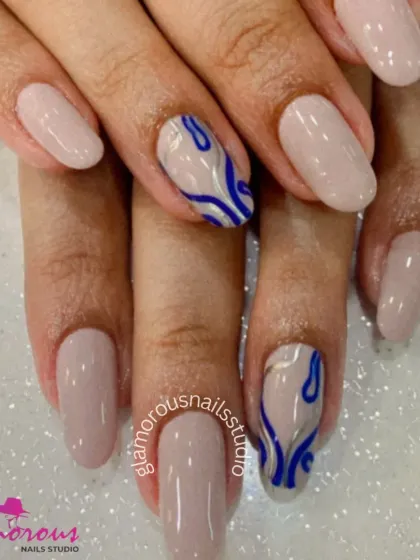 A modern and minimalist design with a pop of color. This set features clean, nude-colored nails with accent nails showcasing an abstract, wavy design in a bold royal blue and silver.