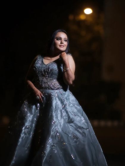 A full-length outdoor portrait of the bride Gunjan at night. The single light source creates a dramatic, spotlight effect, making her look like a star on her special night.