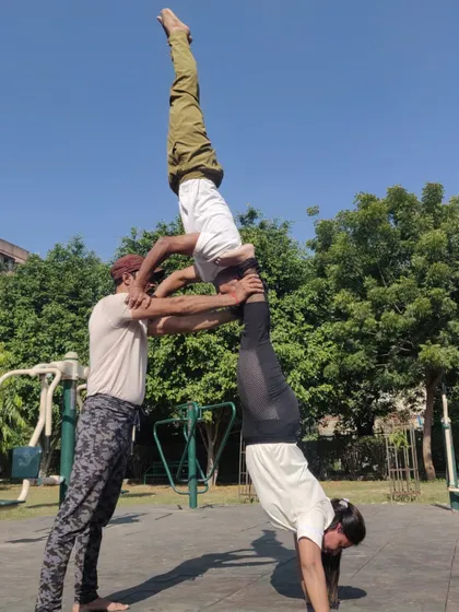 A three-person acro yoga stack, demonstrating advanced balance and strength. I'm in a handstand, supported by one partner, who is in turn supported by another.