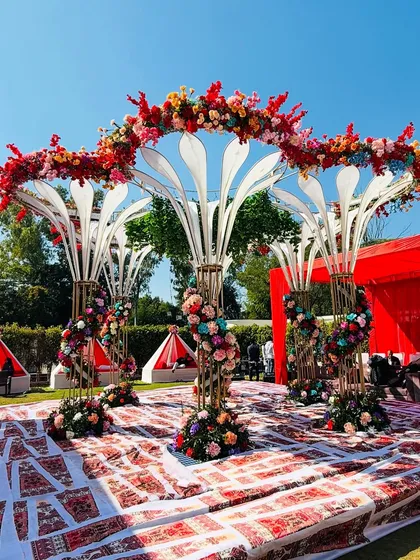 A close-up of the modern mandap structure, showcasing the intricate floral work spiraling up the pillars and across the top.