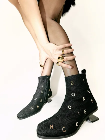 A detail shot focusing on the custom-embellished denim boots from Disobedience. This type of shot is crucial for a product-focused editorial.