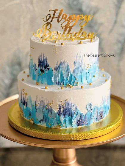 A two-tier cake with a beautiful blue watercolor effect, perfect for a 25th birthday. This was a Kulfi Falooda flavored cake, bringing a unique Indian fusion taste to the celebration.