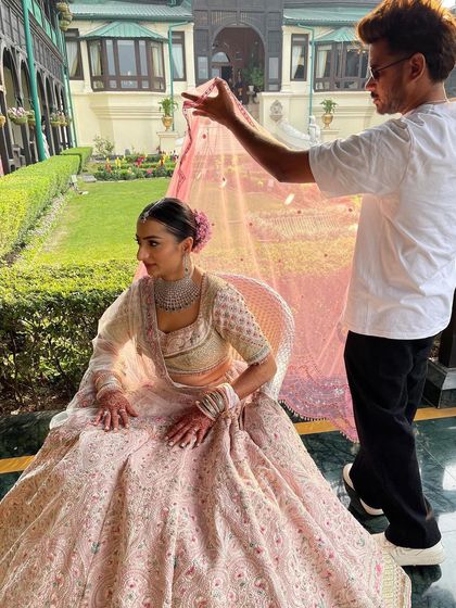 A behind the scenes moment where I am setting the bride's dupatta over her floral bun. I always make sure the hairstyle works with all elements of the bridal attire.