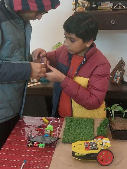 I believe in guiding, not doing. Here, I'm helping a student assemble the electronic components for his solar-powered car, part of his sustainable city project. He learned about circuits and renewable energy firsthand.