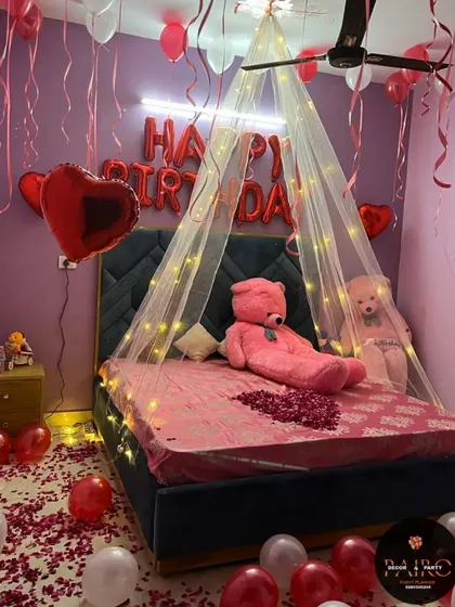 A slightly different angle of the romantic birthday room, showing the heart-shaped foil balloons and hanging ribbons from the ceiling balloons.