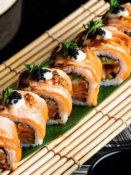 The art of sushi is a delicate dance. Here, our chefs meticulously prepare seared salmon rolls, topped with truffle mayo and caviar, showcasing a commitment to fresh ingredients and refined Japanese techniques.