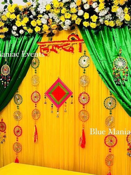 A traditional Haldi setup with a twist. This design uses green and yellow drapes, floral arrangements, and unique dreamcatcher-style hangings for a bohemian touch.