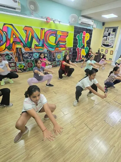 A good posture is key in dance, and we work on it from day one. Here, the kids are practicing a squat position, building strength and focus for their routines.