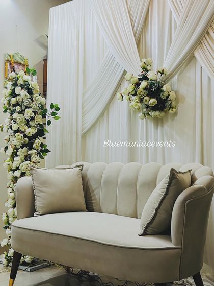 A close-up view of an elegant Roka setup at home. This image highlights the plush velvet loveseat and the dense arrangement of white roses on the floral pillars, showcasing the quality of materials I use.