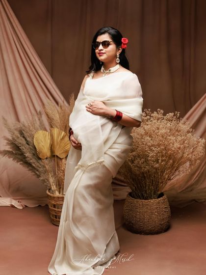 A fun and stylish take on the traditional saree look, with the addition of sunglasses and a confident pose.