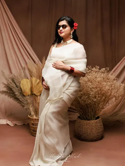 A fun and stylish take on the traditional saree look, with the addition of sunglasses and a confident pose.
