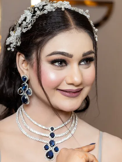 A smiling portrait that captures the joy of the occasion. The makeup is designed to be radiant and photo-ready, with a focus on bright eyes and a flawless complexion.