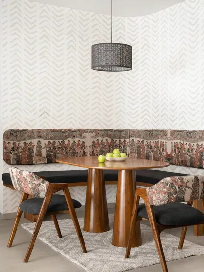 The 'Palaash' dining nook, with its custom built-in bench upholstered in a vibrant tribal print, paired with a solid wood pedestal dining table.