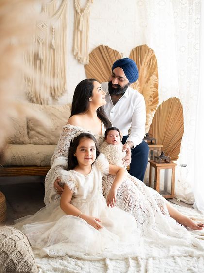 A complete family portrait filled with warmth and love. The parents, their daughter, and their newborn baby gather together in the boho setup for a timeless and heartfelt photo.