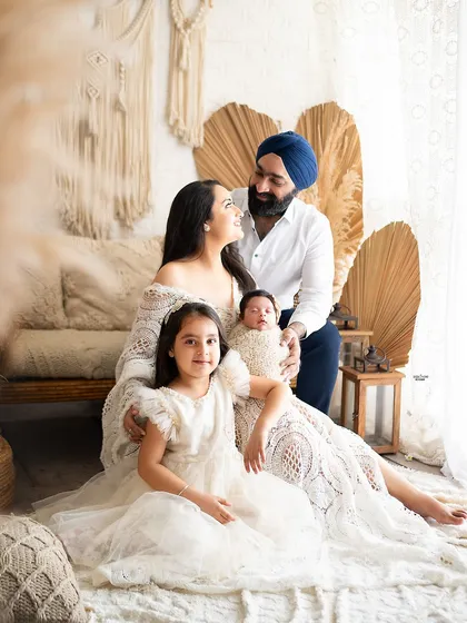 A complete family portrait filled with warmth and love. The parents, their daughter, and their newborn baby gather together in the boho setup for a timeless and heartfelt photo.