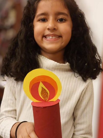 A close-up of a student's smiling face and her lovely Christmas candle. The pride they take in their work is the best part of these festive workshops.