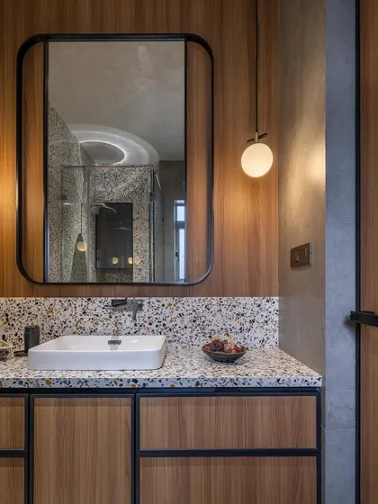 A closer look at the guest bathroom with terrazzo and veneer. The round mirror and pendant lights soften the look, adding a touch of contemporary style.