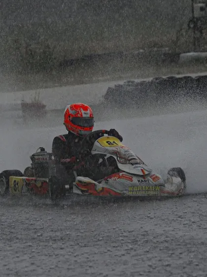 A driver navigates a soaking wet track, showcasing immense car control.