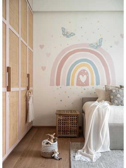 Creating a dreamy haven for a spirited 3-year-old, we embraced her love for pink. The room features a grey sofa bed, blush pink rattan wardrobes, and a hand-painted pastel rainbow on the wall.