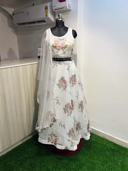 A beautiful white floral lehenga perfect for a summer or day wedding. The organza skirt features a lovely rose print, paired with a sequined blouse and a delicate belt with mirror work.