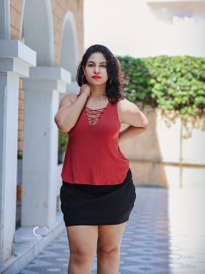 A confident and stylish pose against a backdrop of architectural arches. The play of light and shadow adds dimension to this chic outdoor portrait.